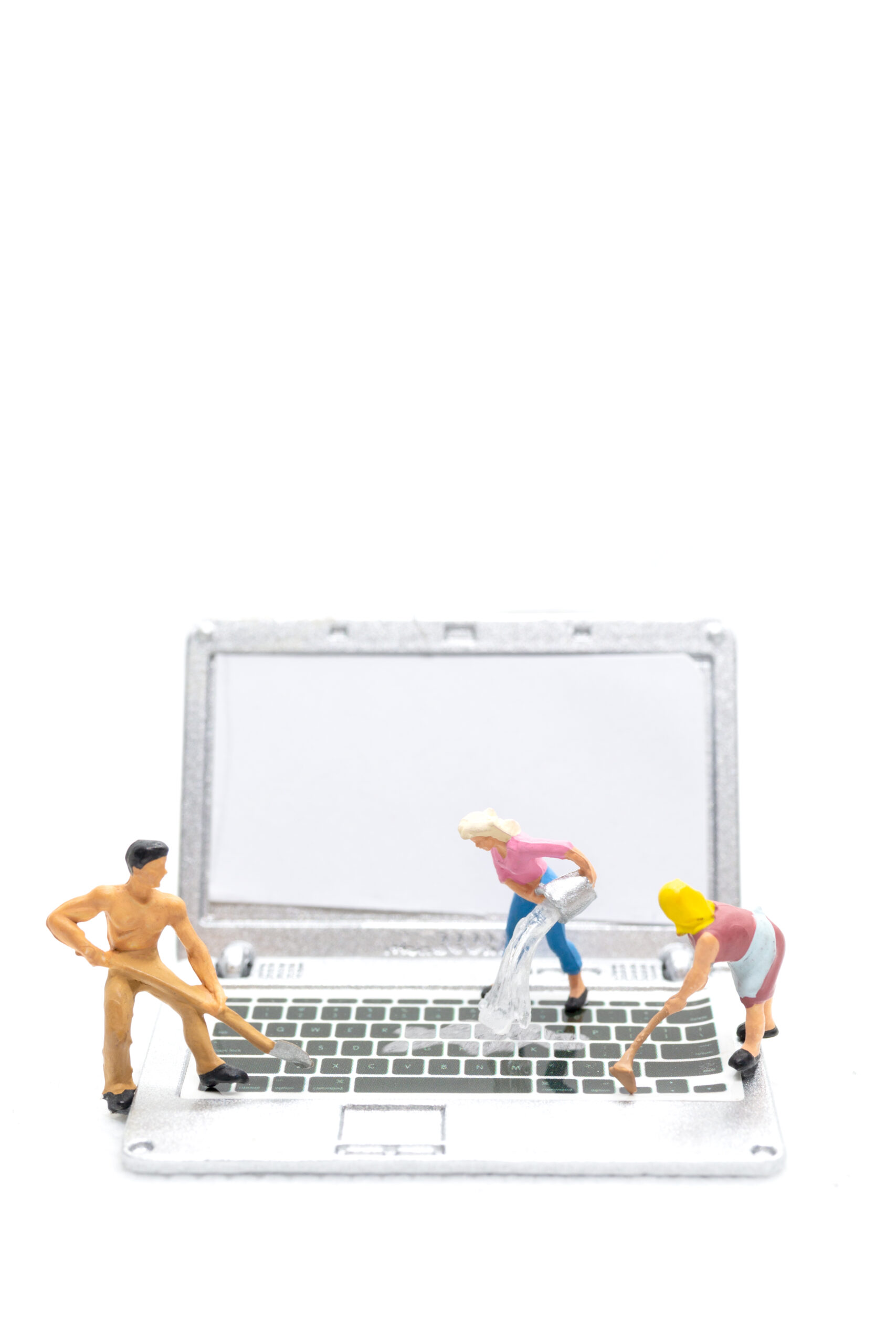 Miniature people cleaning laptop computer on white background